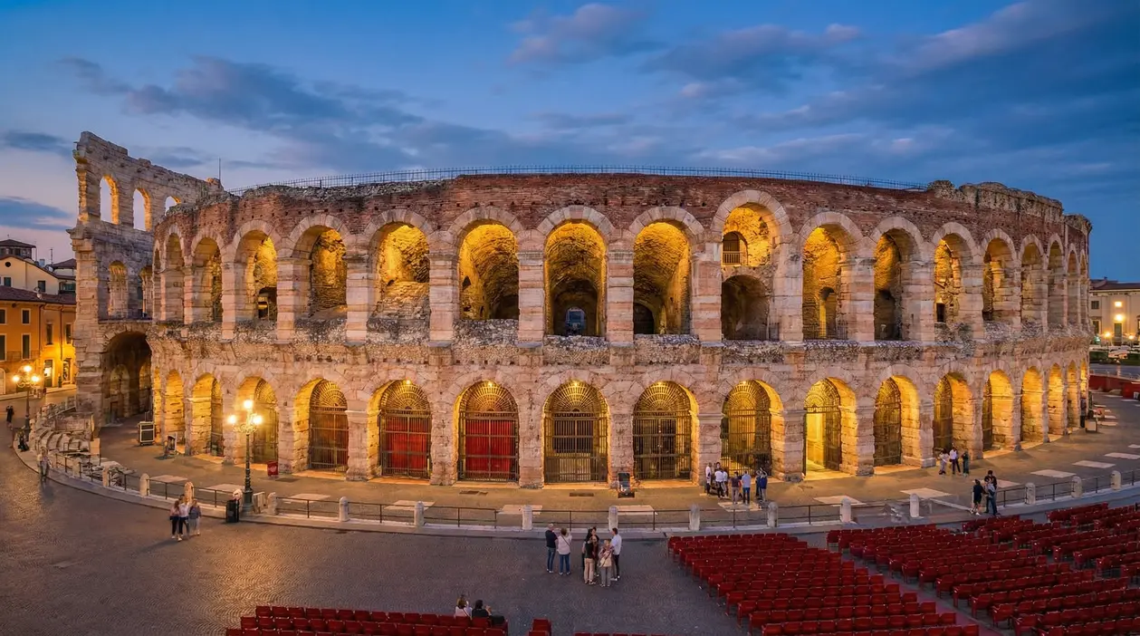 Arena di Verona illuminata al tramonto con poche persone nei dintorni