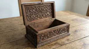 Portagioie in legno antico con intagli decorativi, aperto su un tavolo di legno